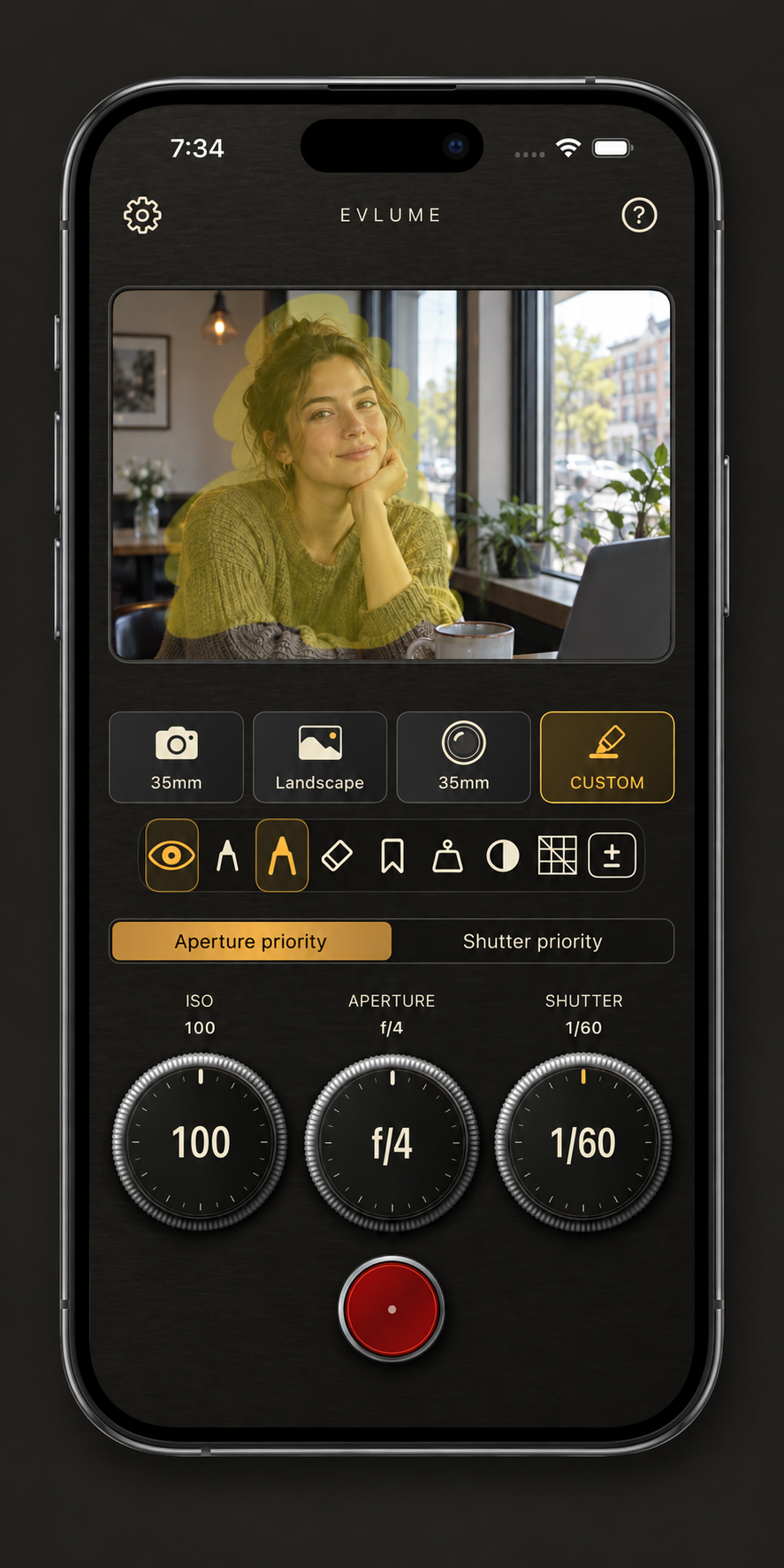 An iPhone displaying an illustrative Evlume Custom preview with a yellow finger highlight over a portrait subject and visible camera and focal-length controls.